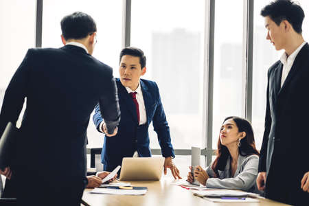 Image two business partners in elegant suit successful handshake together with meeting  group of casual business in modern office.Teamwork conceptの写真素材