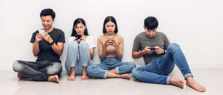 Group of friend sitting relax use technology together of smartphone checking social apps against copy space background.Communication conceptの写真素材