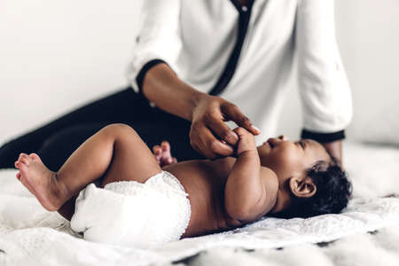 African american mother playing with adorable little african american baby in a white bedroom.Love of black family conceptの写真素材