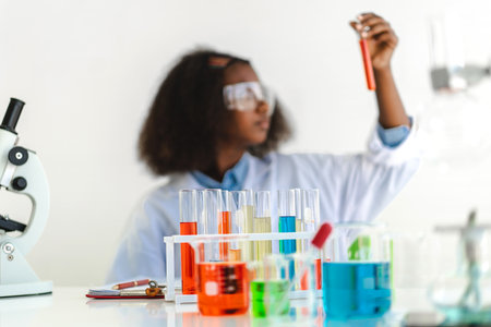 African american girl students learning and doing a chemical experiment and holding test tube in hands in science class on the table.Education conceptの写真素材