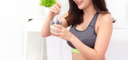 Fitness woman holding yogurt and mixed berries blueberries with strawberries while relaxing at home.dieting concept.healthy lifestyleの写真素材