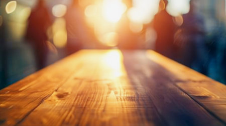 Abstract image of blurred people in motion behind a wooden table, capturing a sense of movement and dynamism while the table remains a stable, grounding element in the sceneの素材