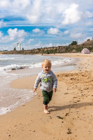 Little boy goes barefoot on the sand at the beach on a warm autumn day.の写真素材