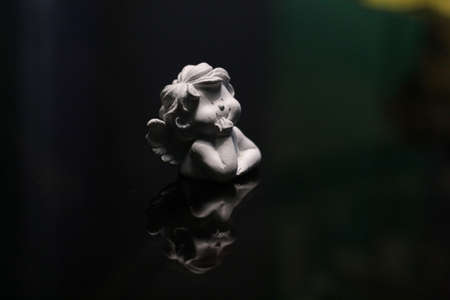Statuette of a small cupid who dreamily looking into space.の写真素材