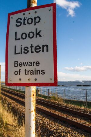 Warning sign by train tracks and the seaの写真素材