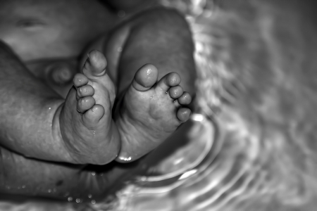 A shot of tiny baby feet in a warm bath tubの写真素材