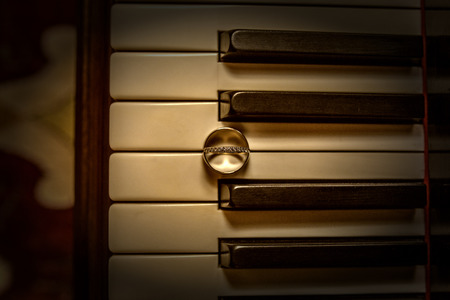 Artistic shot of wedding rings on old pianoの写真素材