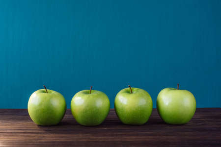 Four green apples on brown wooden background. Copy space placeの写真素材