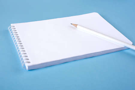 A pencil and a notebook on blue surface. Close up. Copy space for textの写真素材