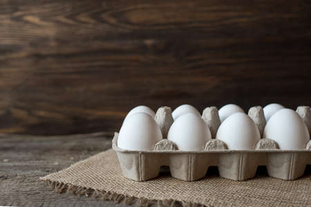 Raw white eggs in egg box on wooden background.の写真素材
