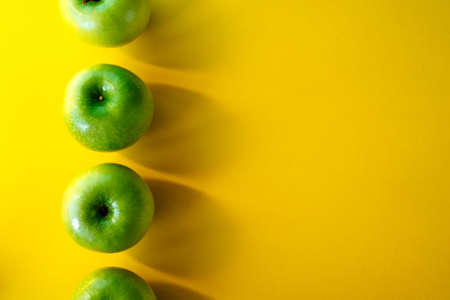 Summer pattern of fresh green apples on yellow background. Copy spaseの写真素材