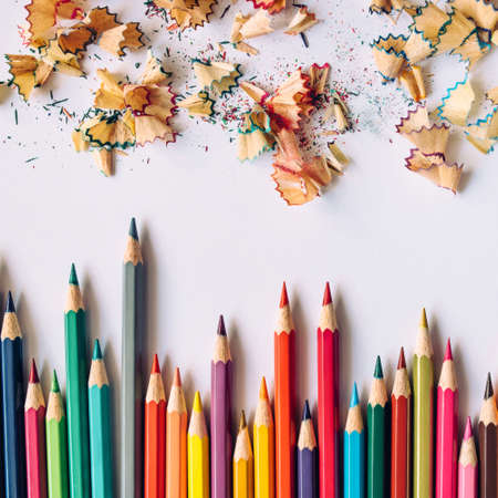 Row of colored sharpened crayons and colored shavings on paper backgroundの写真素材