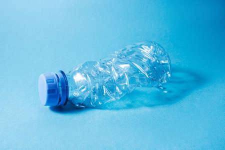 Used disposable plastic bottle on blue background. Eco concept image.