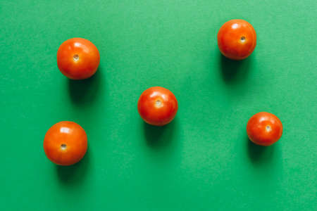 Five cherry tomatoes on a green background. Flat lay.の写真素材