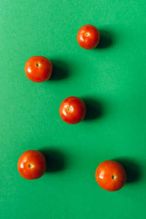 Five cherry tomatoes on a green background. Flat lay.の写真素材