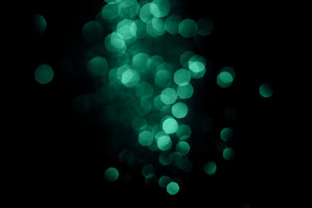 Dark abstract background with bright green bokeh.の写真素材
