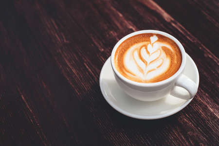Cup of cappuccino with latte art on wooden table. Copy space for your text.の写真素材