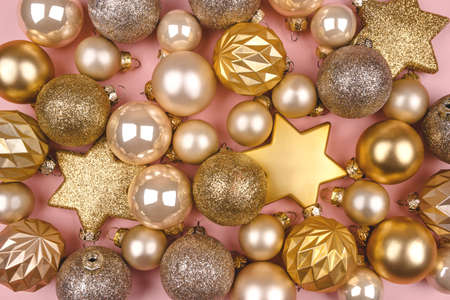 Festive pink background with gold and silver Christmas stars and balls. Flat lay, top view.