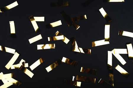 Gold confetti on black background. Flat lay, top view.の写真素材