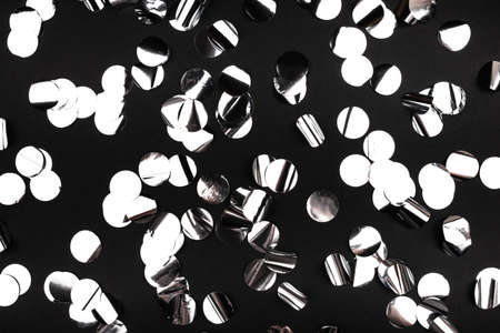 Silver confetti on black background.. Flat lay, top view.