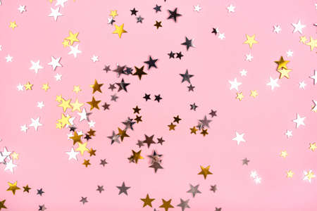 Golden and silver stars on pink pastel background. Flat lay, top view.