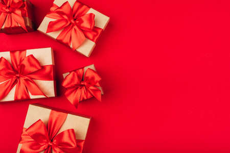 Frame of cardboard gift boxes with bows on red background. Flat lay, top view. Copy space for text.の写真素材