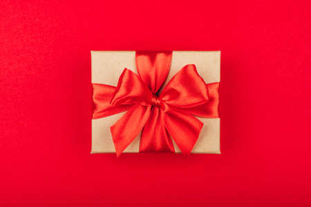 Cardboard gift box with bow on red background. Flat lay. Top view.の写真素材