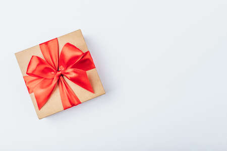 Cardboard gift box with red bow on white background. Flat lay. Top view. Copy space for your text.の写真素材