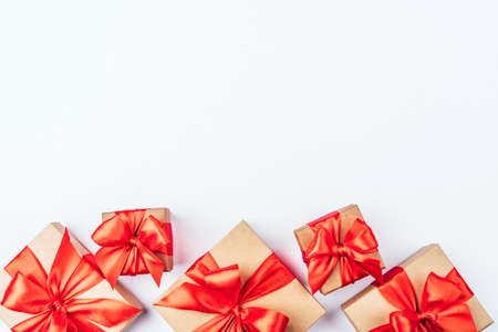 Frame of cardboard gift boxes with red bows on white background. Flat lay, top view. Copy space for text.の写真素材