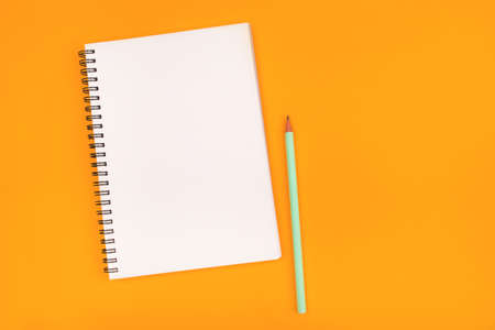 Empty notebook and pencil on orange backgroundの写真素材