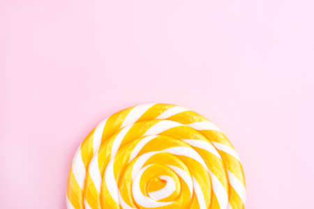 Yellow lollipop in the shape of a circle on a pink background. Flat lay, top view.の写真素材