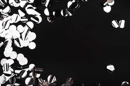 Silver confetti on black background.. Flat lay, top view. Copy space.の写真素材