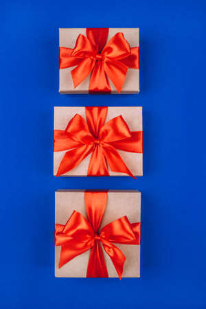 Three cardboard gift boxes with bows on blue background.Flat lay, top view.の写真素材
