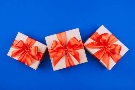 Three cardboard gift boxes with bows on blue background.Flat lay, top view.の写真素材