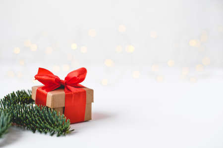 Gift box with a red bow on a background of blurred lights garland. Christmas background.の写真素材