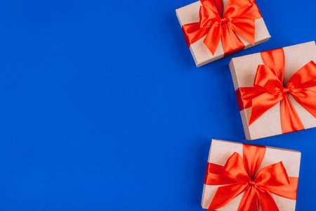 Frame of cardboard gift boxes with bows on blue background. Flat lay, top view. Copy space for text.の写真素材