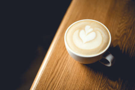Cup of cappuccino with latte art on wooden table.の写真素材