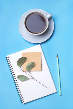 Blue background with notepad, pencil and cup of coffee. Top view, flat lay.の写真素材