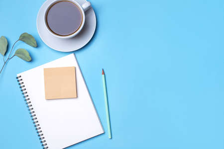 Blue background with notepad, pencil and cup of coffee. Top view with copy space, flat lay.の写真素材