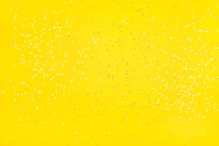 Tiny pearl stars on yellow background. Flat lay, top view.の写真素材