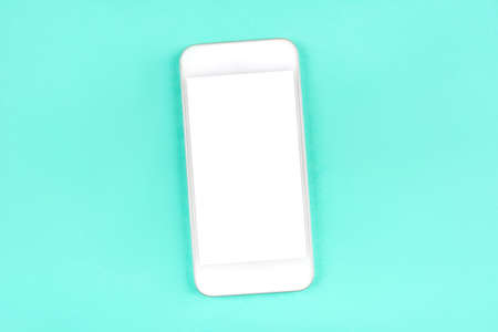 White smartphone on mint background. Flat lay. Space for your text.の写真素材