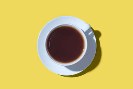 A cup of black coffee or tea on a yellow background. Minimal concept. Flat lay, top view.の写真素材