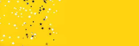Golden and silver stars on yellow background. Flat lay, top view.の写真素材