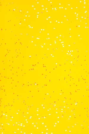 Tiny pearl stars on yellow background. Flat lay, top view.の写真素材