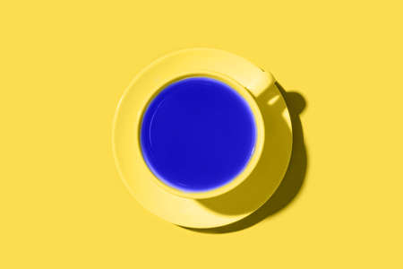 A cup of black coffee or tea on a yellow background. Minimal concept. Flat lay, top view.の写真素材