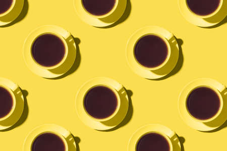 Pattern of cups of black coffee or tea on a yellow background. Flat lay, top view.の写真素材