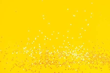 Tiny pearl stars on yellow background. Flat lay, top view.の写真素材