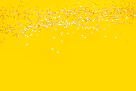 Tiny pearl stars on yellow background. Flat lay, top view.の写真素材