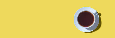 A cup of black coffee or tea on a yellow background. Minimal concept. Flat lay, top view.の写真素材