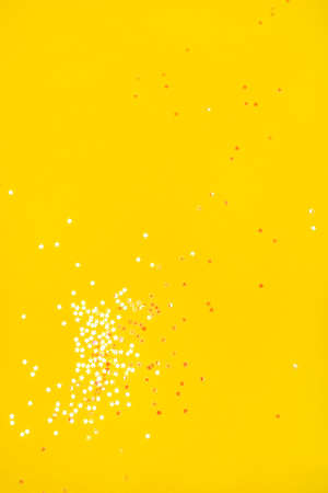 Tiny pearl stars on yellow background. Flat lay, top view.の写真素材